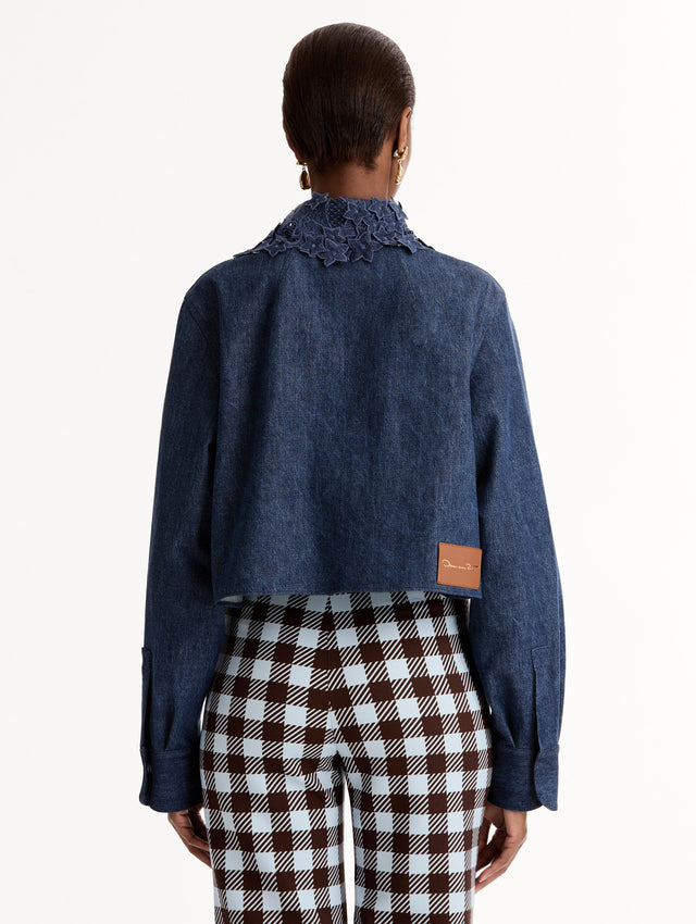 Cropped denim jacket with intricate porcelain flower threadwork and cutout detailing across the front and collar. Long sleeve. Back View.