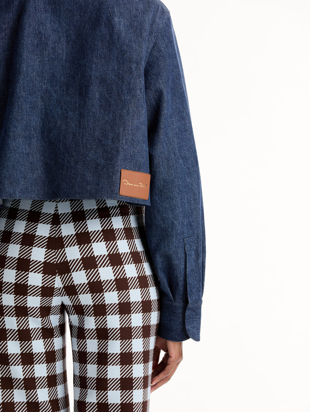 Cropped denim jacket with intricate porcelain flower threadwork and cutout detailing across the front and collar. Long sleeve. Back View, Close Up.