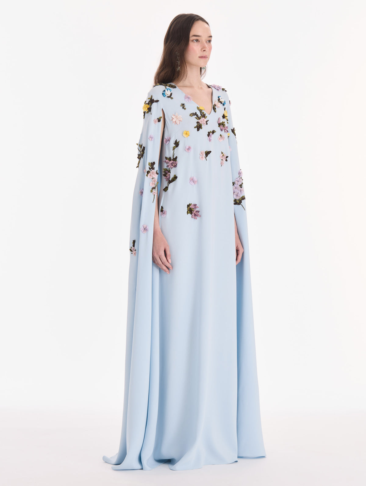 The model is wearing a draped sleeve mixed botanical on lace caftan. Side view.