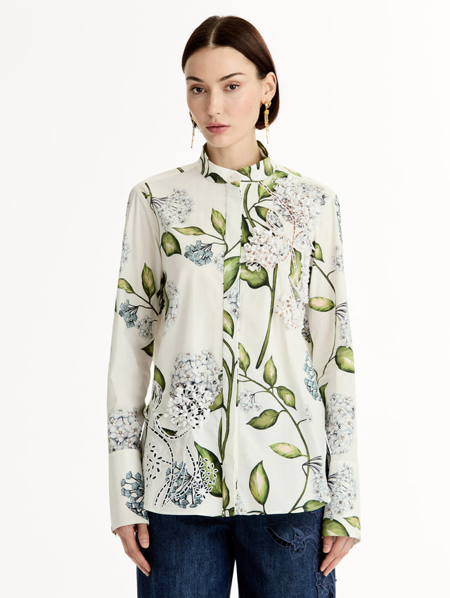 Porcelain flower print on cotton poplin blouse. Tailored silhouette and concealed button front. Threadwork cutout detailing. High Neckline. Front View.