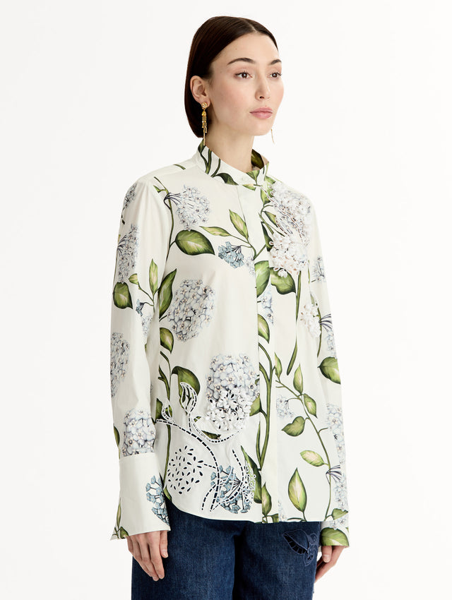 Porcelain flower print on cotton poplin blouse. Tailored silhouette and concealed button front. Threadwork cutout detailing. High Neckline. Side View.