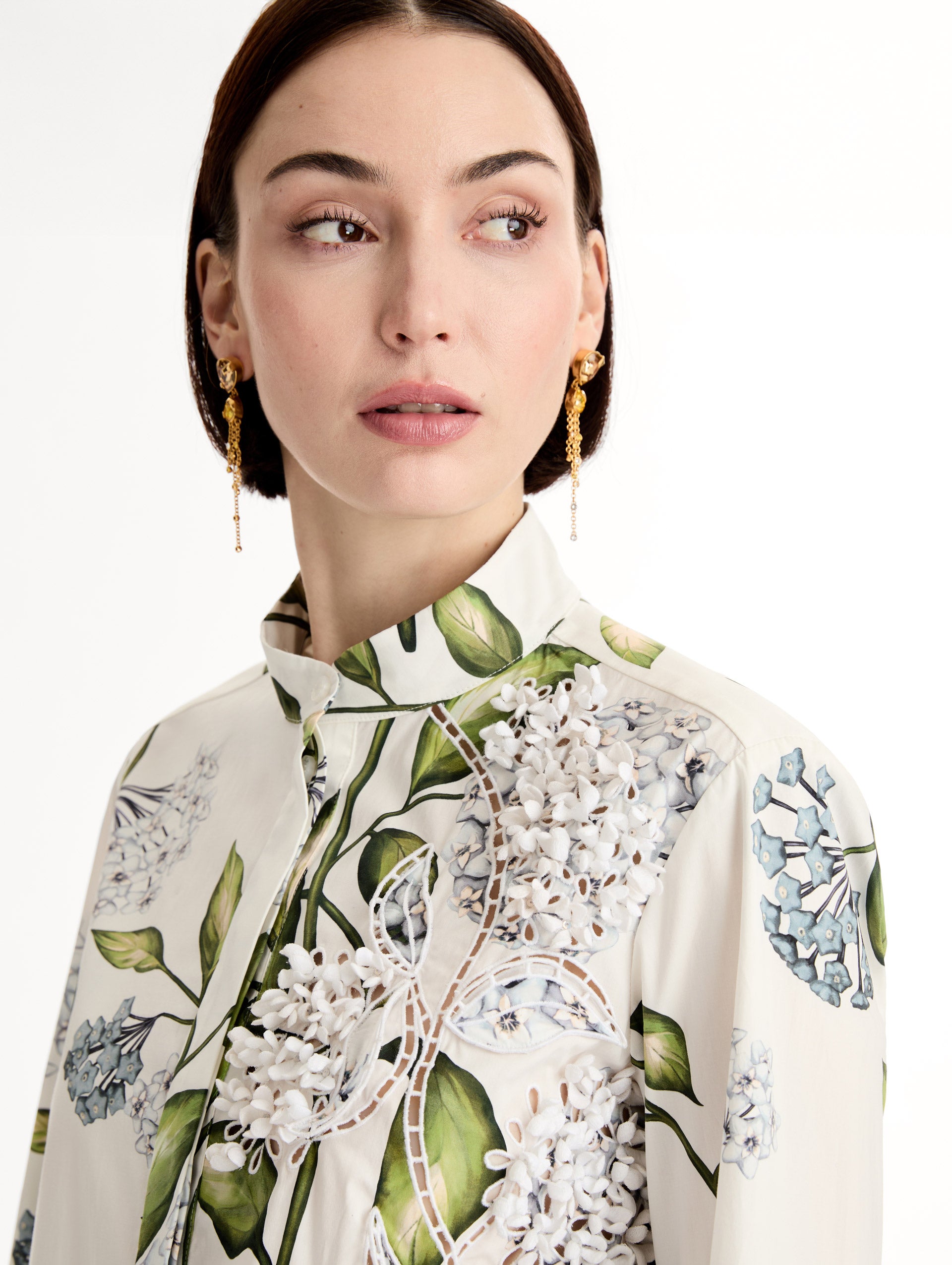 Porcelain flower print on cotton poplin blouse. Tailored silhouette and concealed button front. Threadwork cutout detailing. High Neckline. Side View, Close Up.