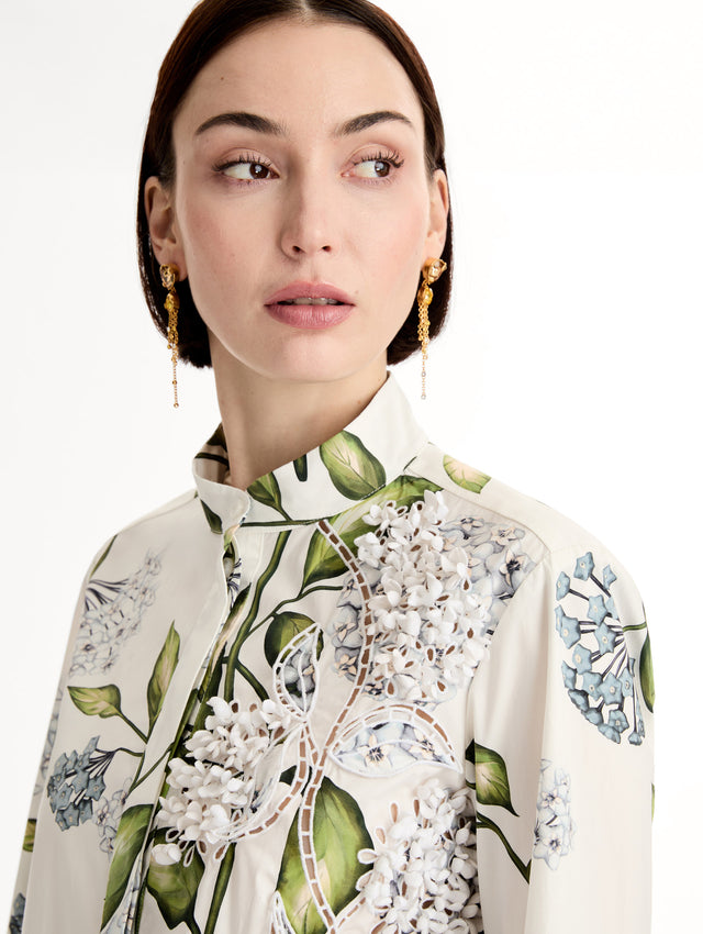 Porcelain flower print on cotton poplin blouse. Tailored silhouette and concealed button front. Threadwork cutout detailing. High Neckline. Side View, Close Up.
