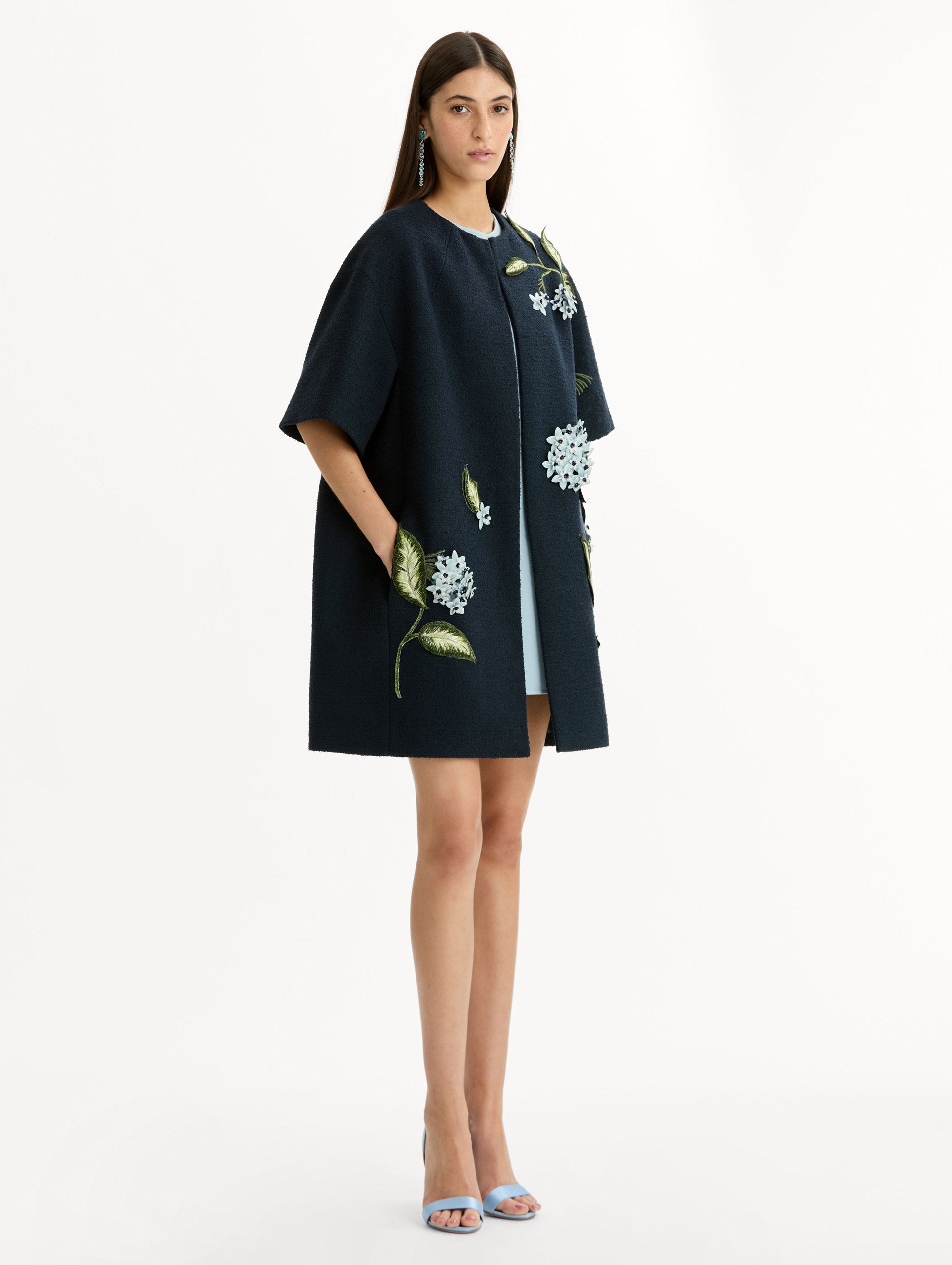 Short sleeve, navy tweed coat with porcelain flower embroidery. Floral motifs cascade across the front. Side View. 