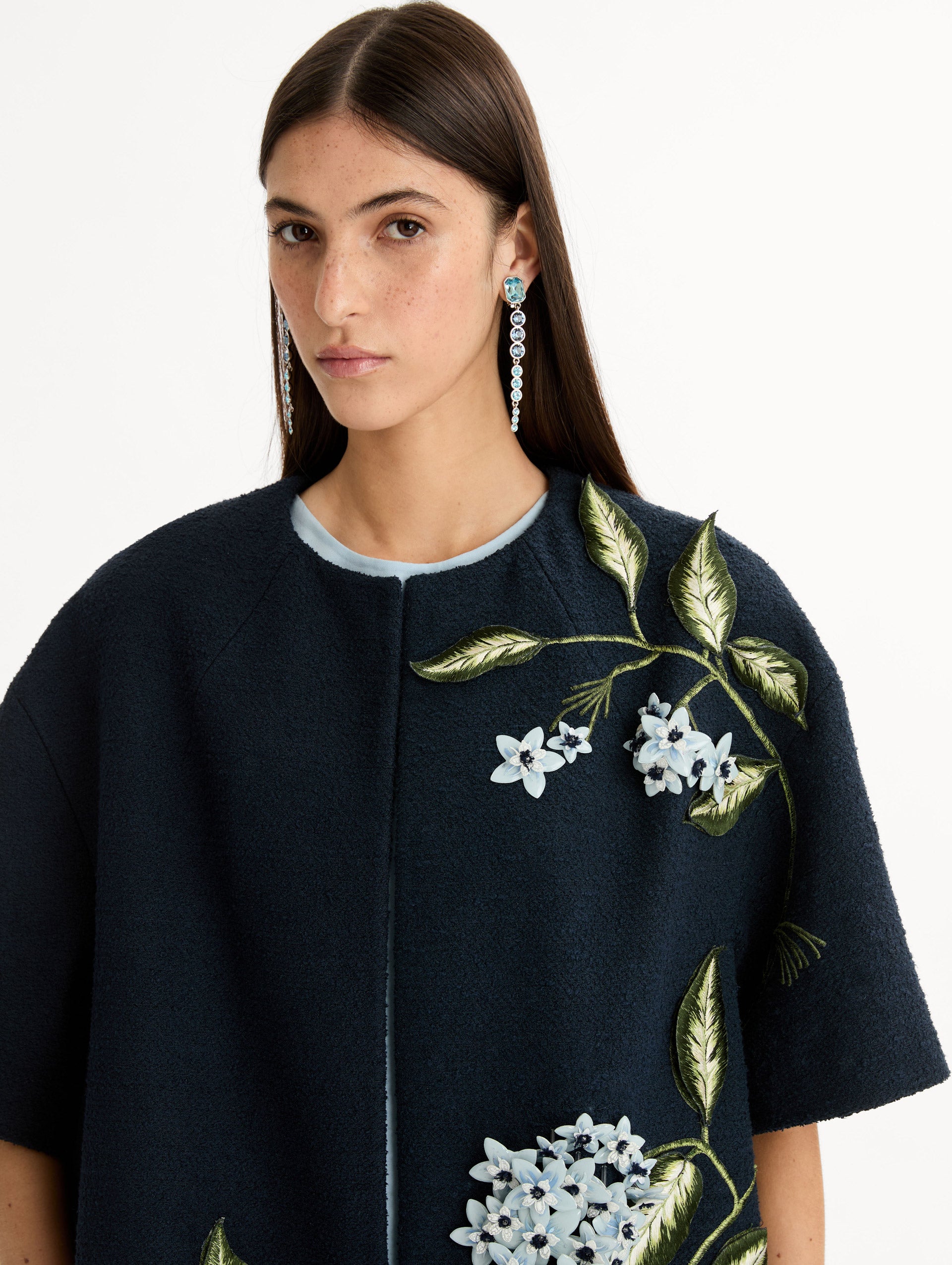 Short sleeve, navy tweed coat with porcelain flower embroidery. Floral motifs cascade across the front. Close Up Front View. 