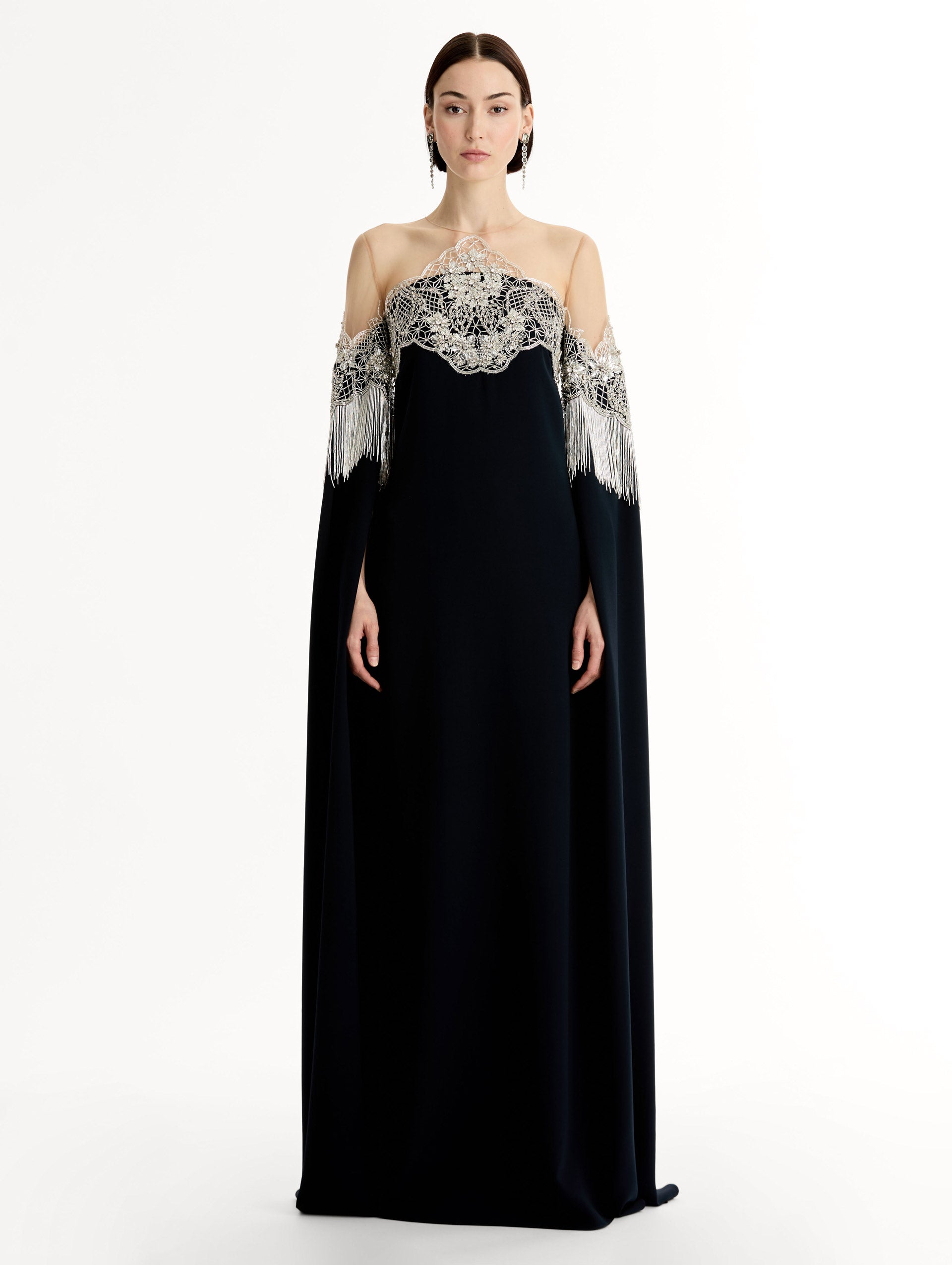 Caftan with sheer illusion tulle neckline and porcelain flower lattice. Hand-applied bugle beads around each motif, and fluid bugle bead fringe on sleeves. Front View. 