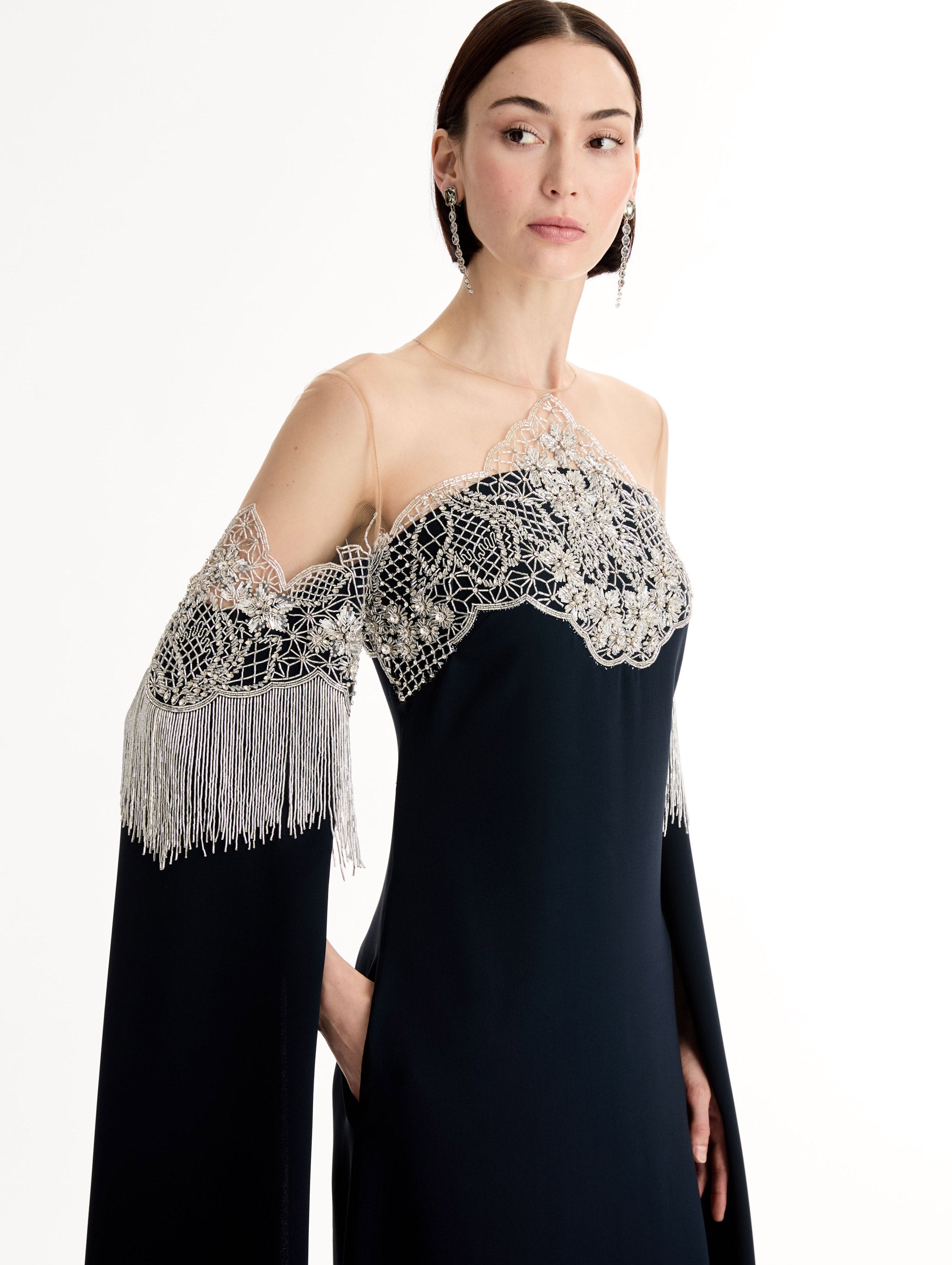 Caftan with sheer illusion tulle neckline and porcelain flower lattice. Hand-applied bugle beads around each motif, and fluid bugle bead fringe on sleeves. Close Up Side View. 