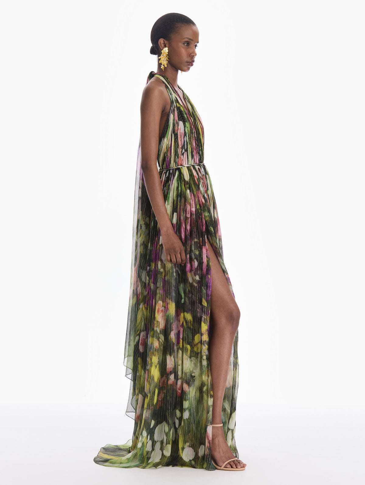 The model is wearing a sleeveless abstract landscape chiffon gown. Side view.