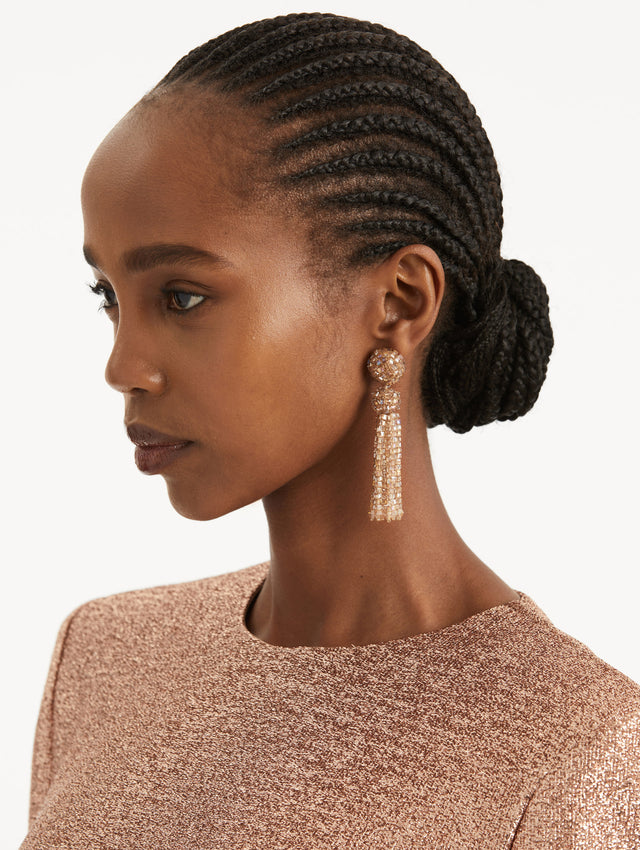 Model is wearing tassel earrings which cascade in sculptural strands, each crystal carefully strung to catch the light. Finished with crystal-strung post.