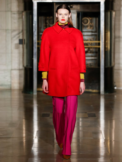 A model wears a red coat with pink pants and yellow turtleneck