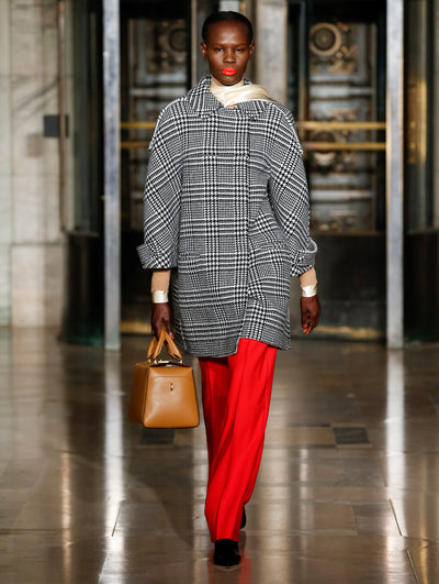 A model wears a black and white coat with red pants