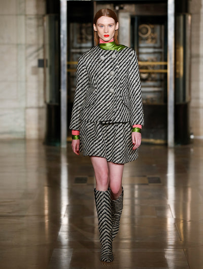 A model wears a striped grey and black skirt and jacket set with matching boots