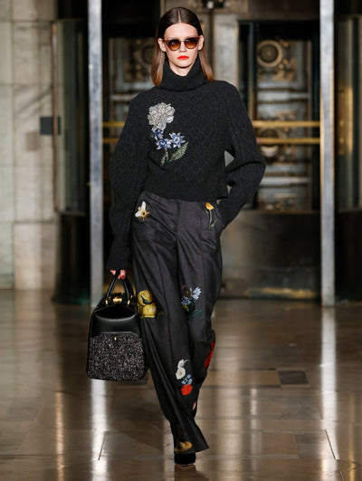 A model wears black pants and cardigan with printed flowers