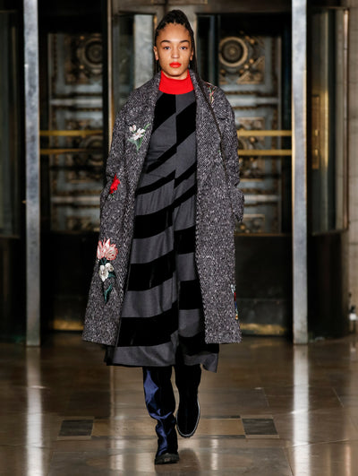 A model wears a black and grey striped dress and coat with red turtleneck