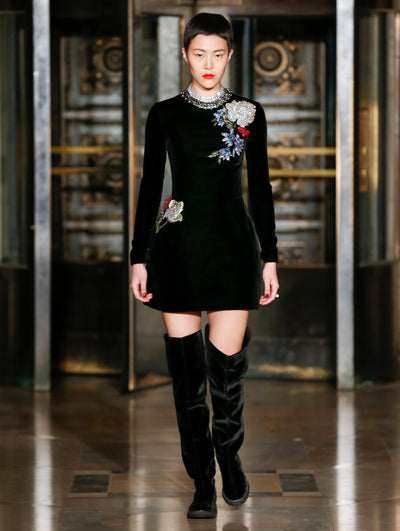A model wears a black velvet dress with embroidered dress