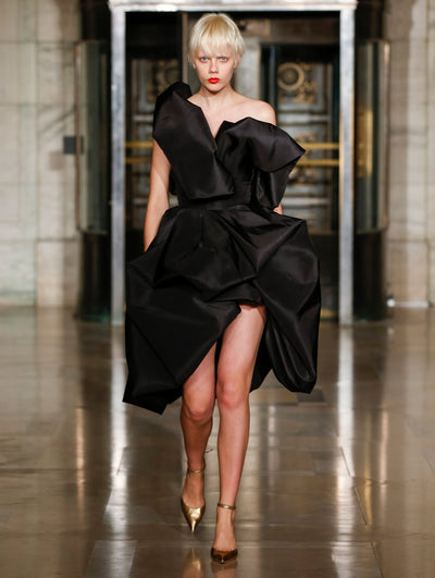 A model wears a black cocktail dress with ruffles