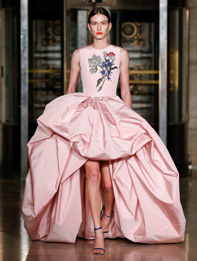 A model weas a pink gown with embroidered flowers on the top