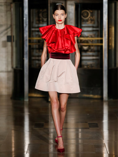 A model wears a dress with a silk ruffle top and cream skirt