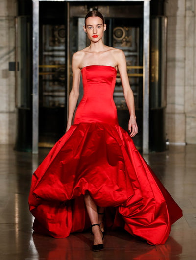 A model wears a red silk gown with a voluminous skirt