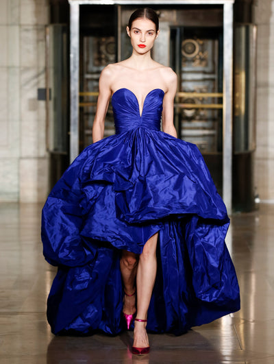 A model wears a blue gown with a voluminous skirt