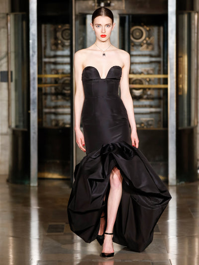 A model wears a black gown with ruffles on the bottom