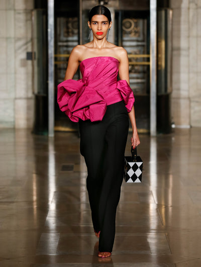 A model wears black pants with a pink ruffle top
