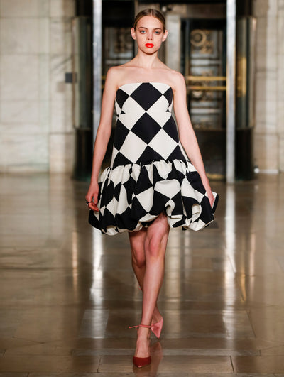 A model wears a black and white cocktail dress with geometric shapes