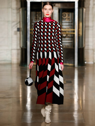 A model wears a dress with dark orange black and white geometric shapes