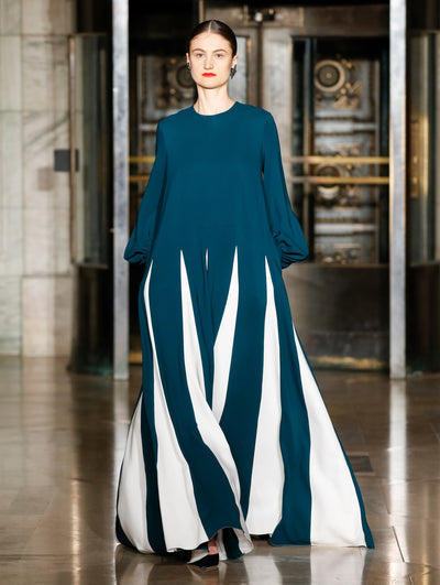 A model wears a gown with white and navy stripes on the bottom