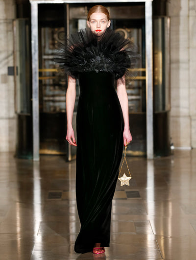 A model wears a black dress with ruffles around the neck
