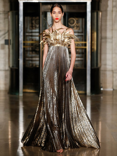 A model wears a gold dress with feathers at the bust