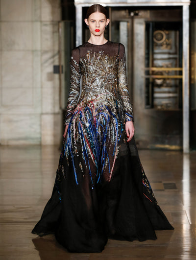 A model wears a black dress with sparkle motifs embroidered