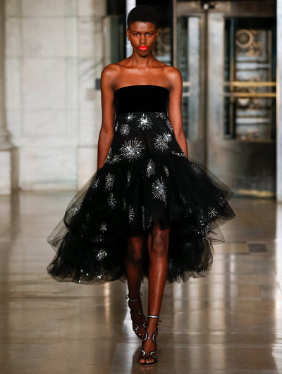 A model wears a black dress with sparkle motifs embroidered