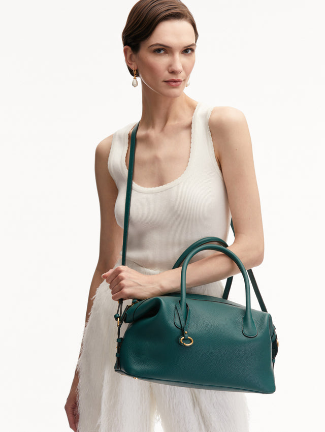 Model Holding the Dahlia Leather Handbag in Green with Detachable Shoulder Strap and O logo tag around the Top Handle.  Front View