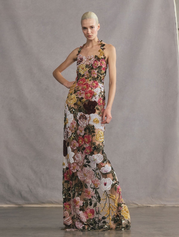 The model is wearing a floral beaded, halter-neck gown.