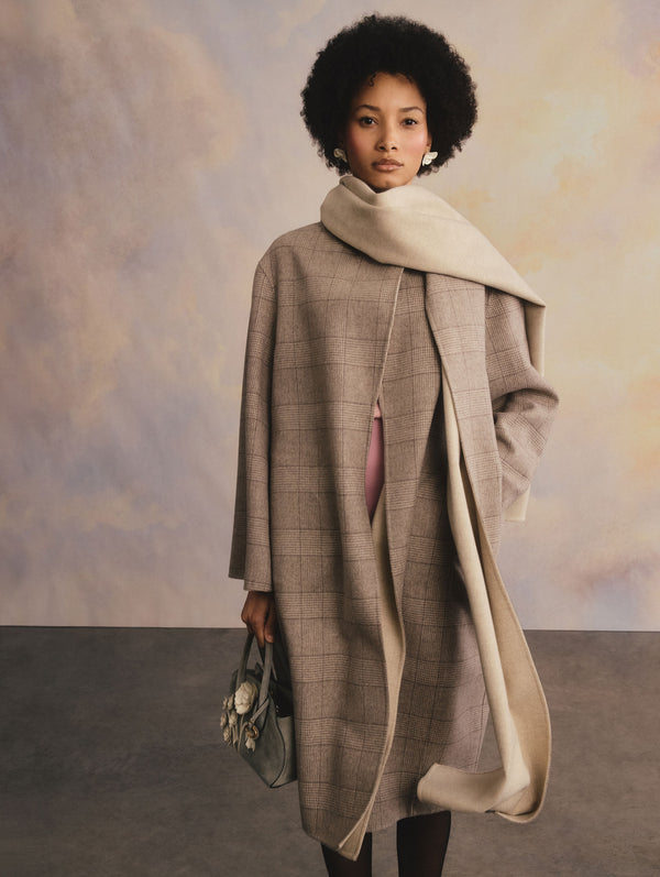 The model is wearing a brown plaid coat with a matching scarf.