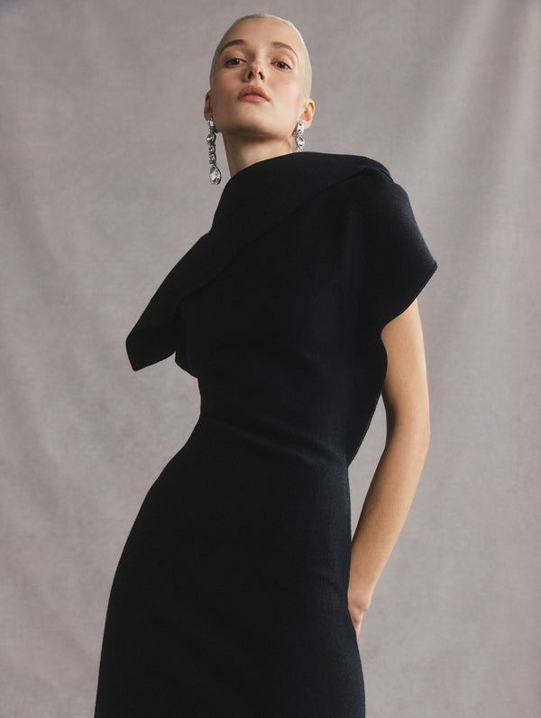 The model is wearing a black drape neck slim knit dress.