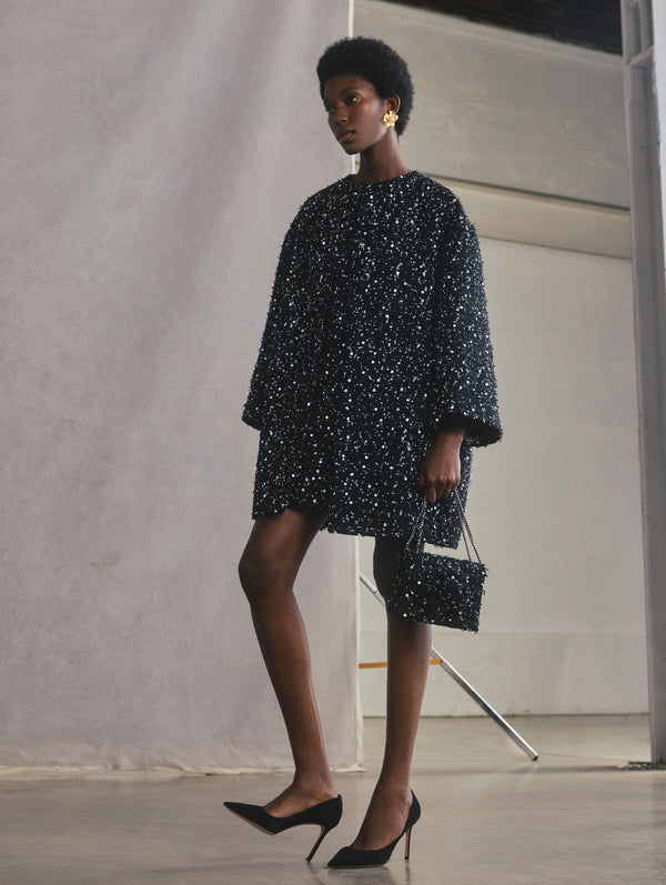 The model is wearing a long sleeve peony silk twill short coat and is holding a matching handbag.