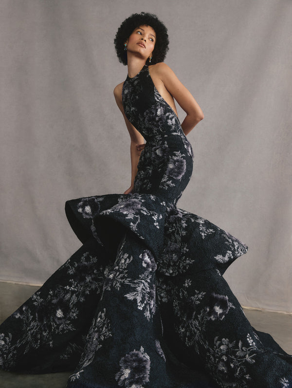 The model is wearing a sleeveless printed peony tiered mermaid gown.