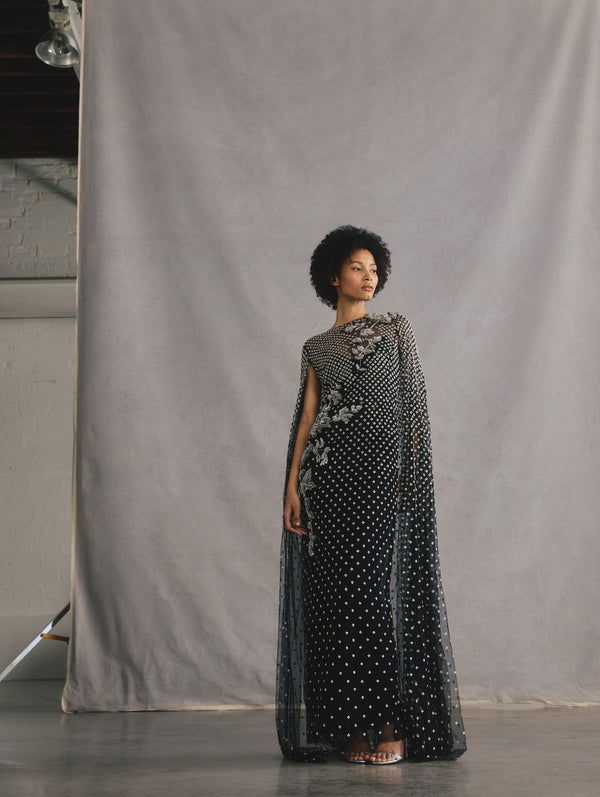 The model is wearing a black and silver long sleeve mixed botanical threadwork caftan.
