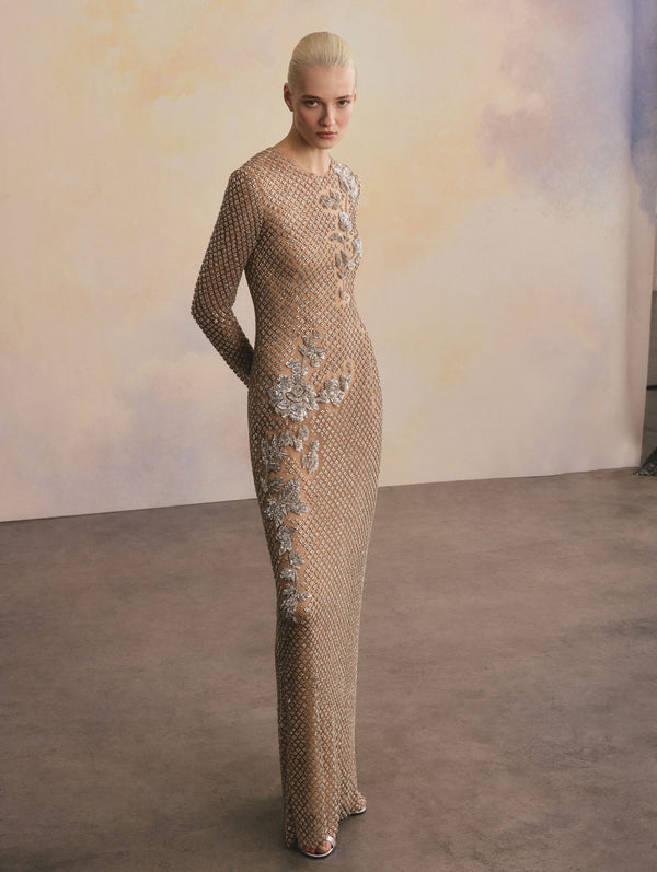 The model is wearing a nude and silver long sleeve crystal grid florals embroidered gown.