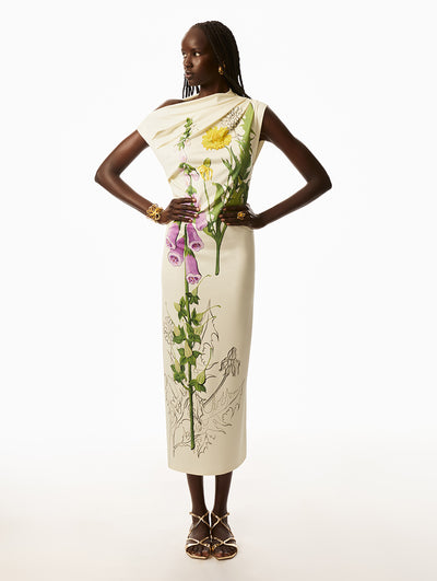 Model is wearing ivory dress with printed pink and yellow florals with gold wire bracelet and ring.  