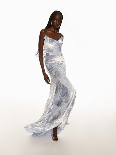 Model wearing a silver velvet dress with velvet silver feathers and silver earrings. 