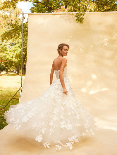 The model wears a strapless tulle wedding gown with floral embroidered.