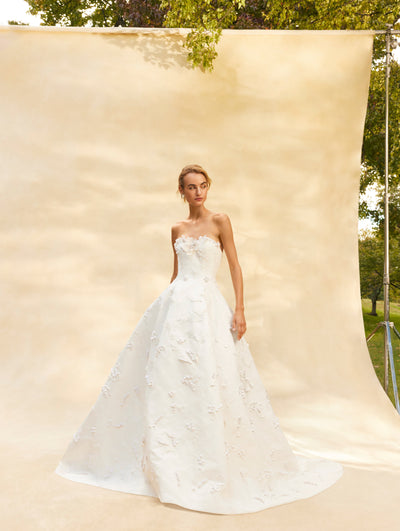 The model is wearing a strapless tulle wedding gown with embroidered floral details. Front view