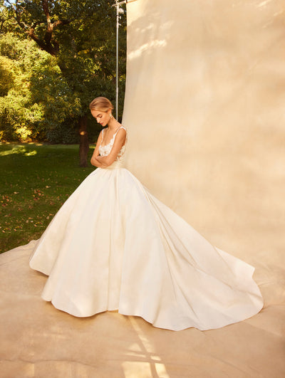 The Model wears a wedding gown with a full puffy skirt and lace details in the top.