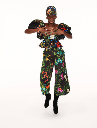 A model poses against a white backdrop in an Oscar de la Renta floral blouse and matching trouser set. 