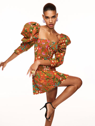 A model poses against a white backdrop in an Oscar de la Renta floral mini dress.