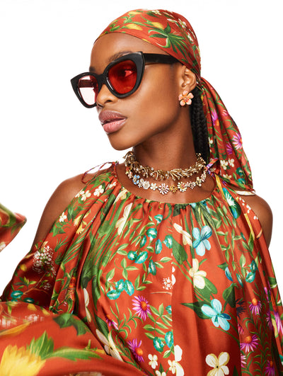 A model poses against a white backdrop in an Oscar de la Renta floral printed dress and matching hair tie. 