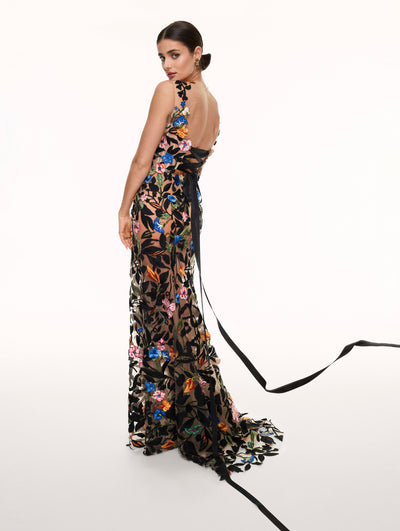A model poses against a white backdrop in an Oscar de la Renta floral embroidered gown. 
